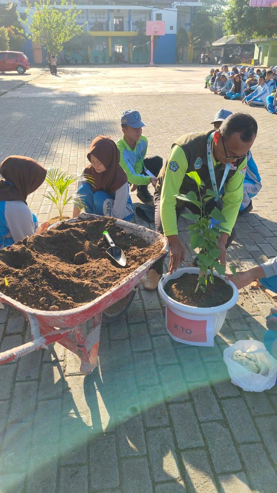 Belajar dan Praktik Menanam Pohon "MPLS SMKN 2 Banjarbaru Tahun 2026/2027" Bersama Bapak H.Daryanta, S.Pd., M.M. Ketua DPW HPAI Banjarbaru di Halaman SMKN 2 Banjarbaru